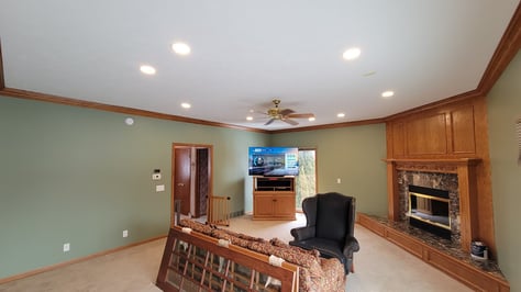 Living room painted sage green with golden oak trim and white ceiling.