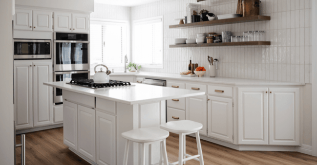 Kitchen with white painted cabinets, tile, and countertops.
