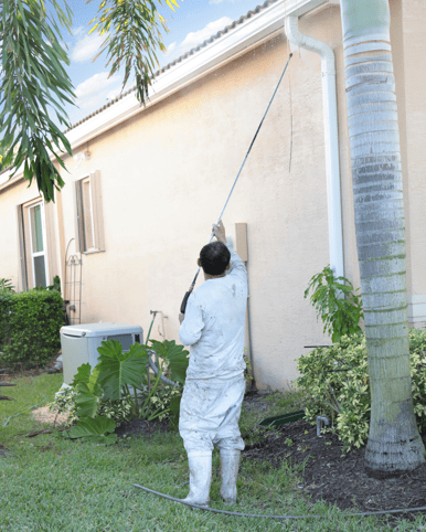 Painter spraying exterior of home for power washing services in Omaha.