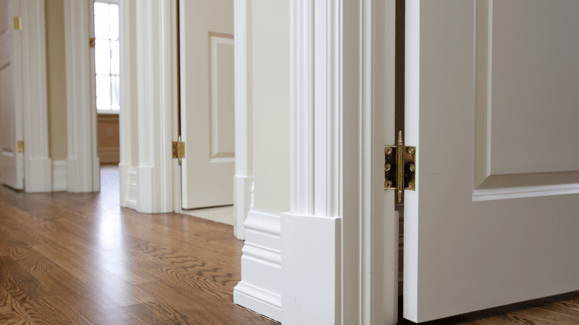 White baseboards and interior doors in a hallway of an Omaha home with wooden floors..