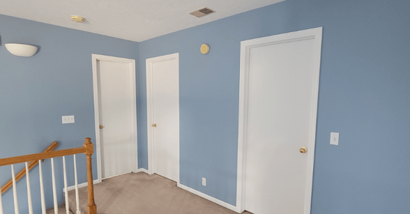 Interior hallway painted a baby blue color on walls with white trim and interior doors.
