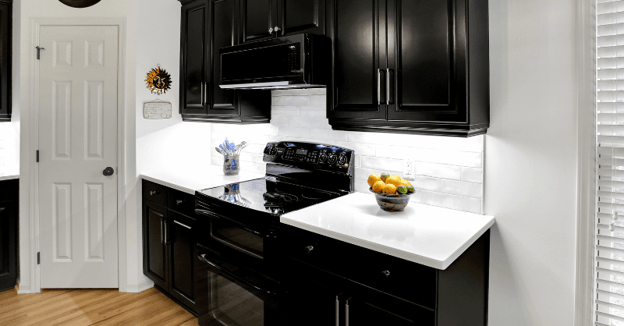 Glossy finish on black painted cabinets in a kitchen with white countertops and backsplash.