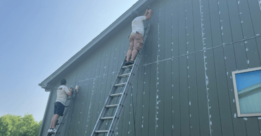 Brush & Roll Painting employees caulking the exterior of a home before painting.