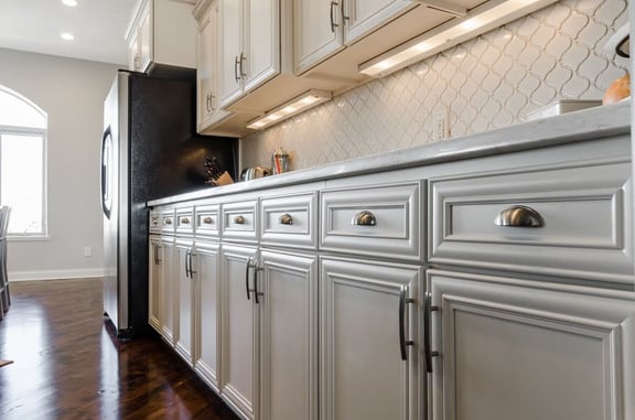 White kitchen cabinets and white backsplash with led under cabinet lighting under the upper cabinets.