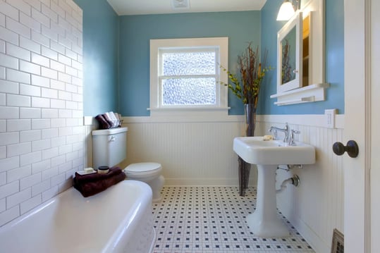 Bathroom with light blue walls and white floors, tile, shower, and toilet.