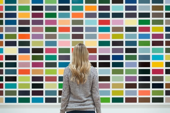 Woman standing in front of wall of paint colors picking one for her painting project.