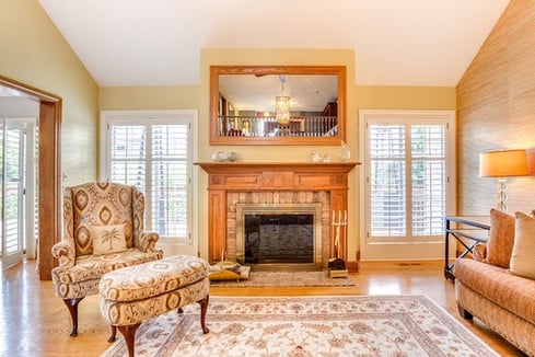 Living room with golden oak trim and woodwork around stone or brick fireplace.