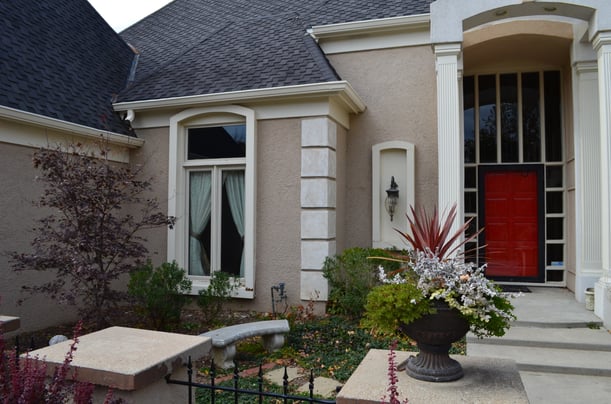 Grey roof with light brown siding and a red front painted door.