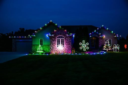 Multi colored Christmas lights with yard art on the outside of a home in Omaha, NE.