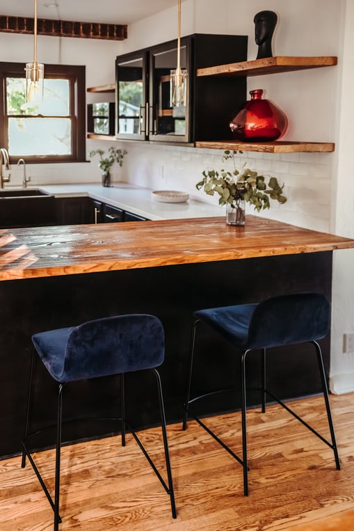 Black painted kitchen island and light wooden countertops and floors.