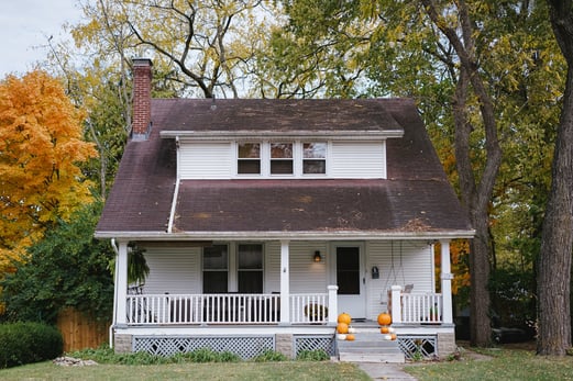 White house in the fall with pumpkins on the porch.