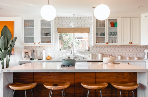 Kitchen with marble countertops on a wooden island and white cabinets.