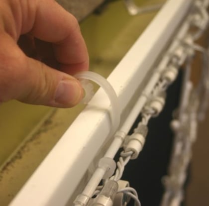 Person installing strands of lights with a s clip.