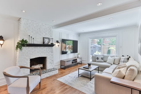 Light living room with a white brick fireplace and walls and a light wooden floor.