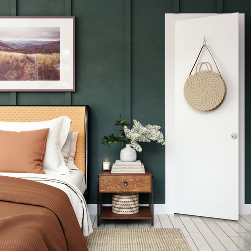 Bedroom with hunter green painted walls, a bright white door, and brown colored bedding.