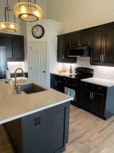 Kitchen with white walls and black cabinets. The kitchen has white countertops and white backsplash.