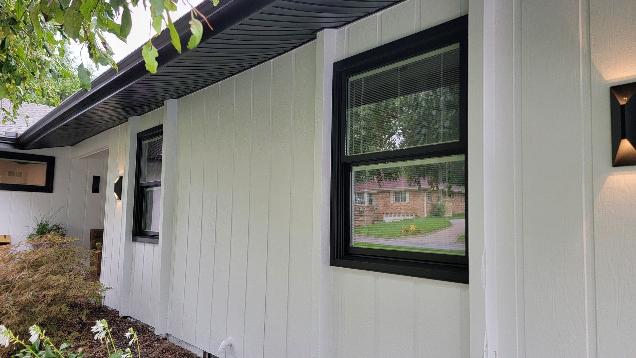 Exterior side of a home painted white with black trim on windows.