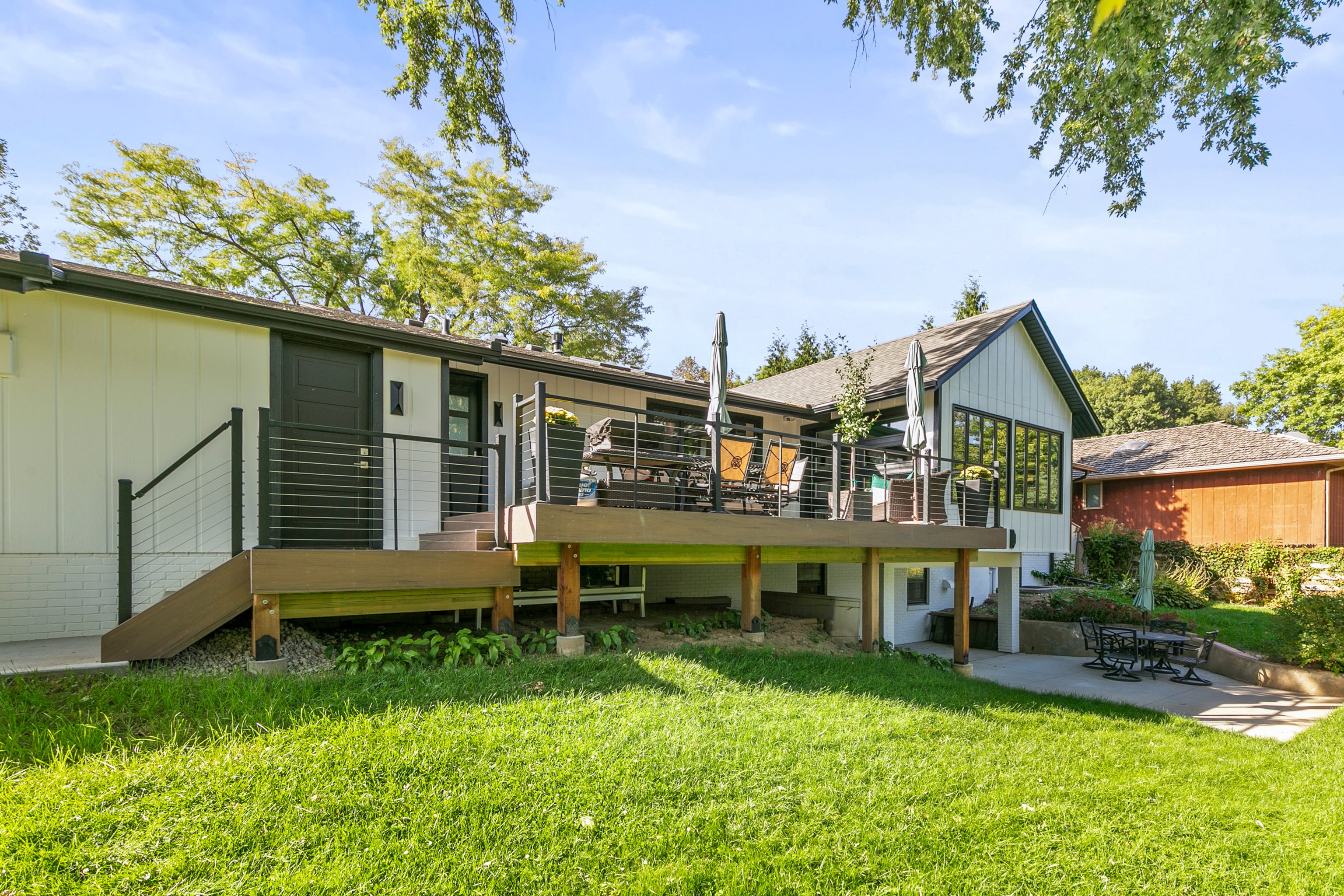 Light wood deck with black railings attached to a white house with black trim.