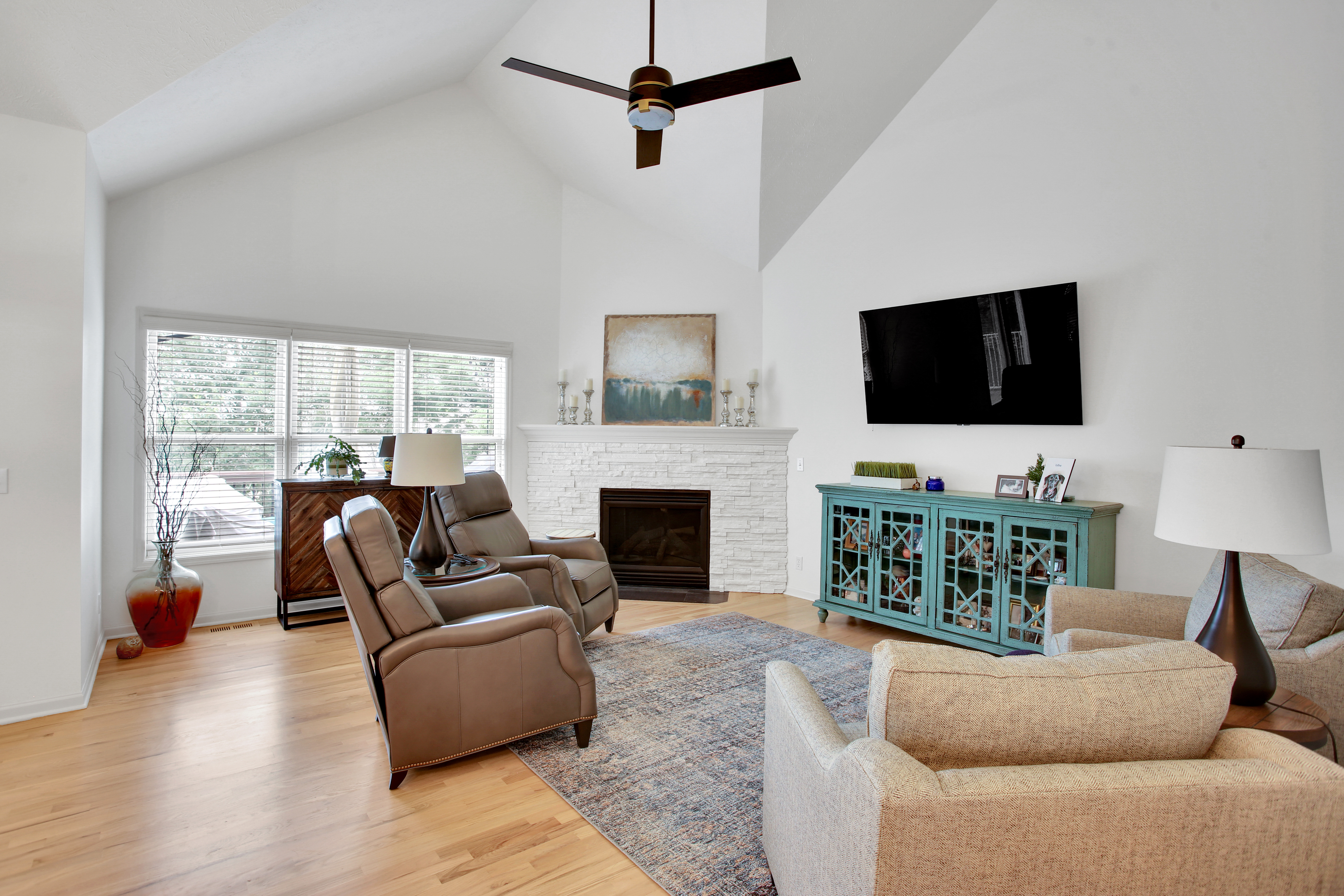 Interior living room with white painted walls and ceiling and fireplace along back wall and TV.