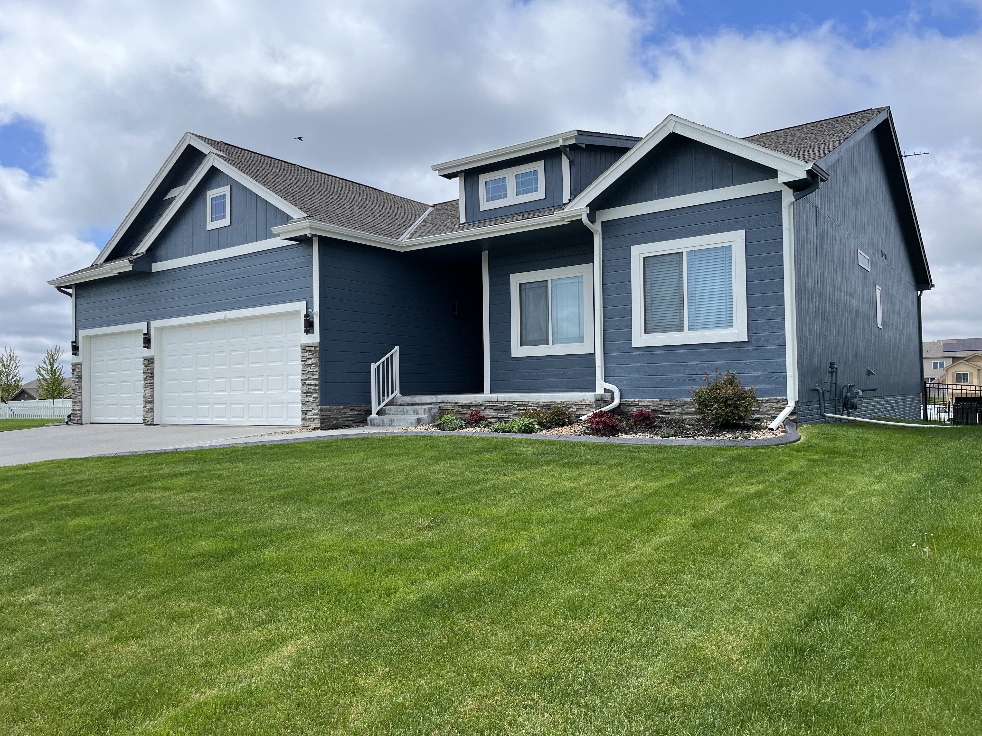 Exterior of home in Omaha painted dark blue with white trim on windows and garage.