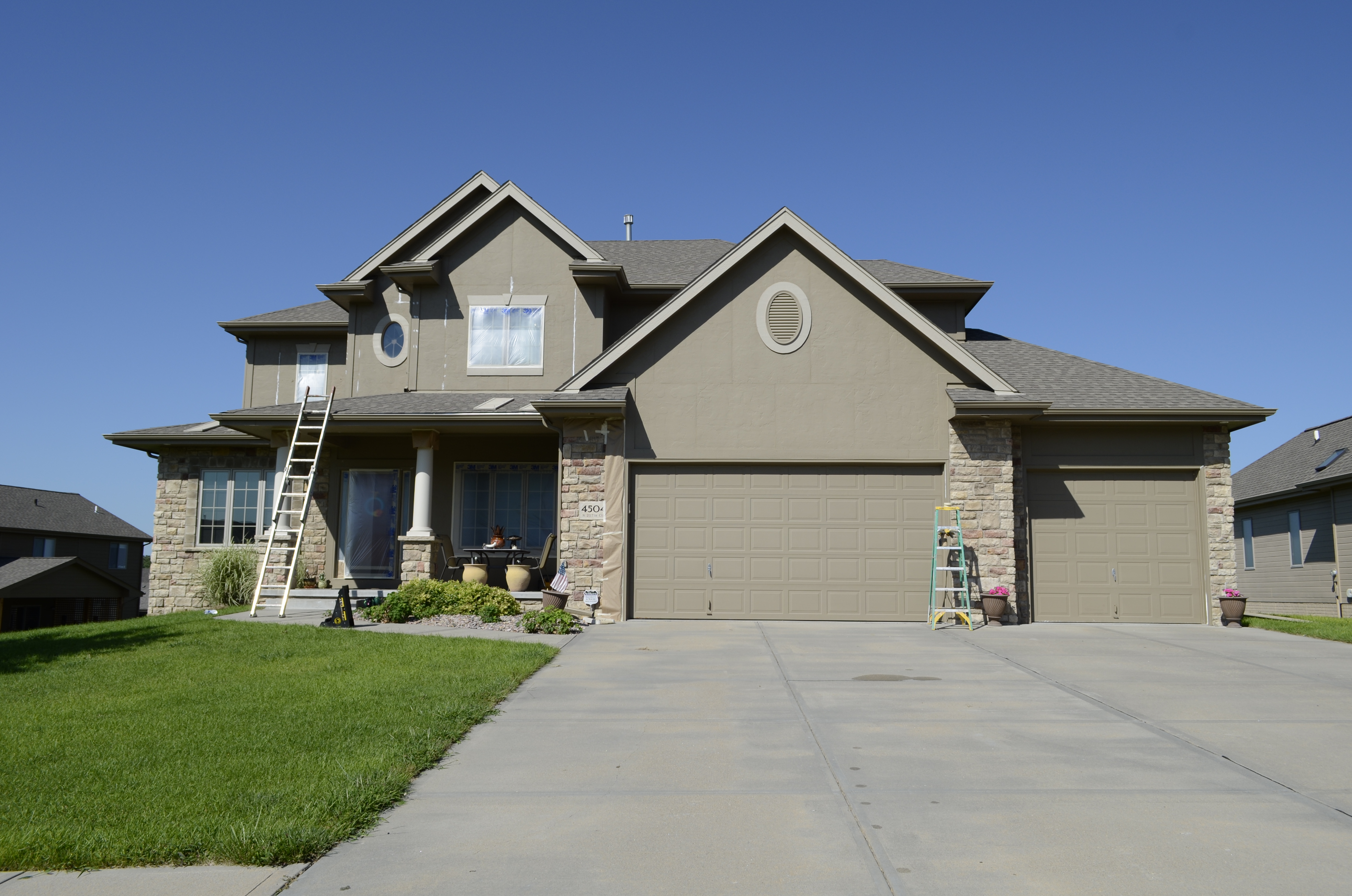 Light brown exterior of a house with latter on the left side.