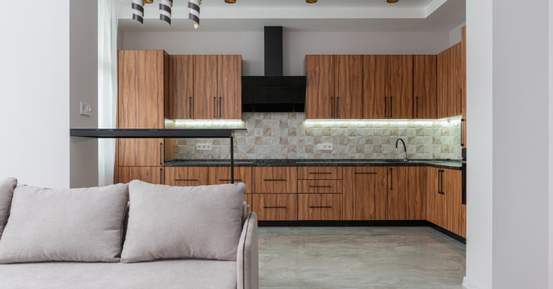 Kitchen with warm brown stained MDF wood with black stove hood and countertops.