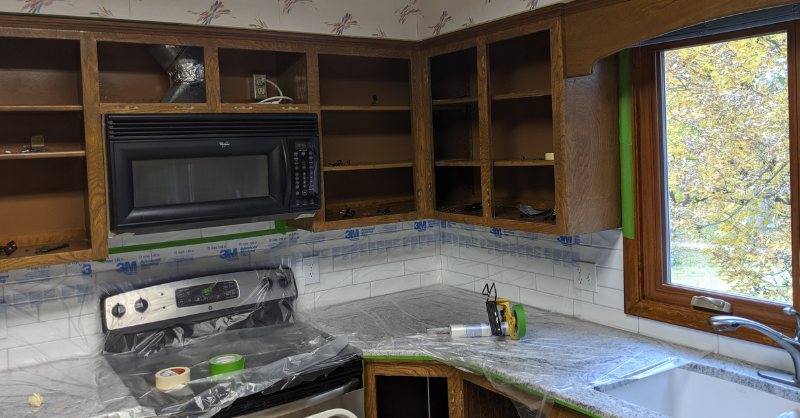 Kitchen with brown cabinets with no doors and are empty and plastic on countertops.