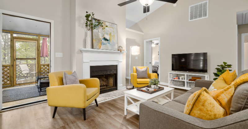 Living room with white fireplace, beige walls, grey couch, and mustard colored chairs.
