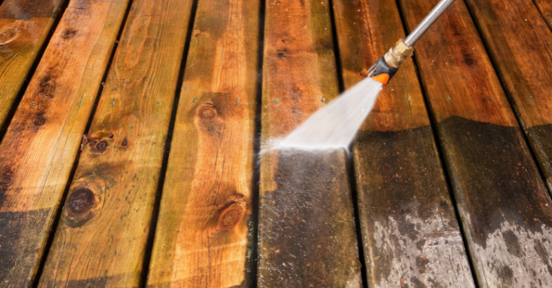 Power washer hitting dirty deck boards to clean them.