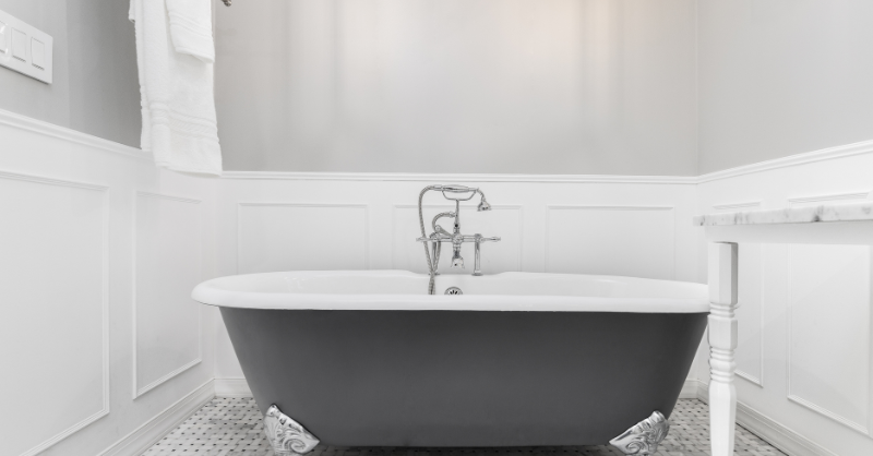 Bathroom with a black tub and color blocked walls with upper half light grey and bottom board and batten painted white.