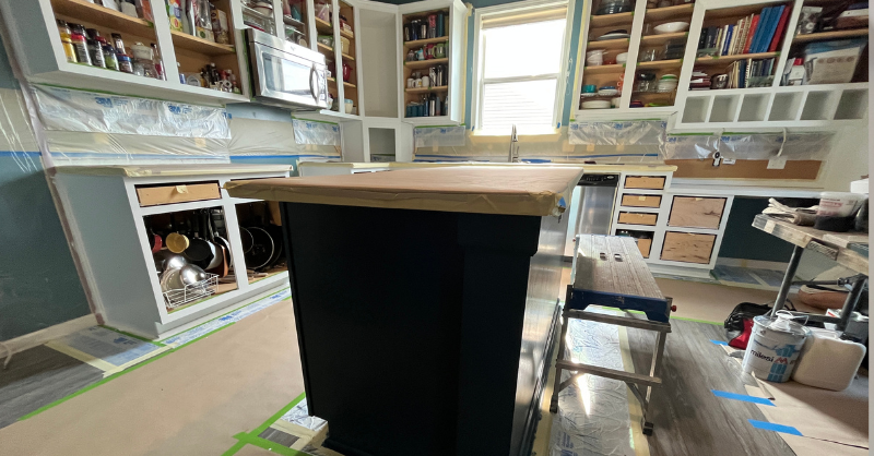 Renovated kitchen with cabinet doors and drawers removed and paper covering countertops.