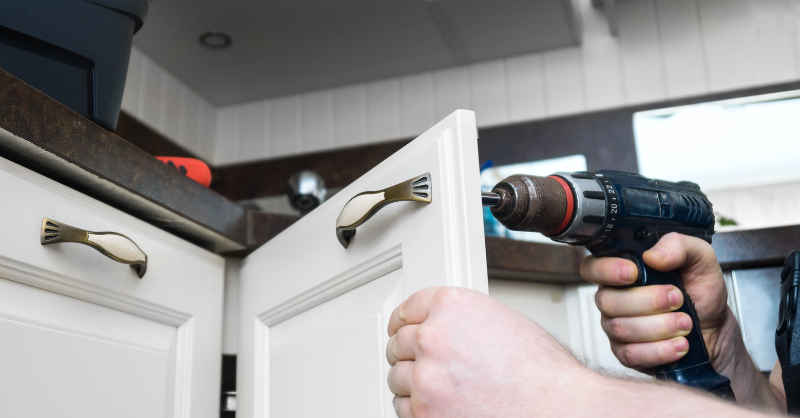 Painter installing a handle on a white painted cabinet door in Omaha. 