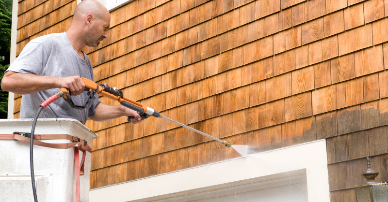 Man power washing exterior of house with a pressure washer in Omaha, NE.