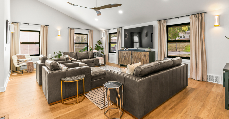 Interior living room in a home painted a grey off white color with dark furniture and light warm wooden floors.