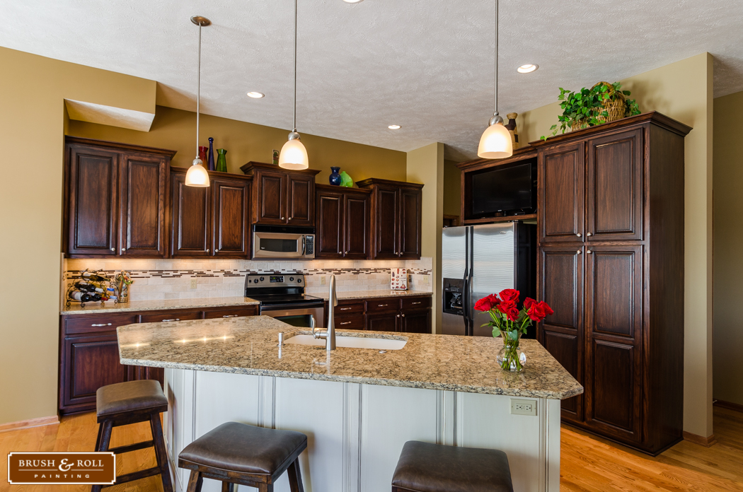 Kitchen with darker toned cabinets along back walls and a white island in the center.