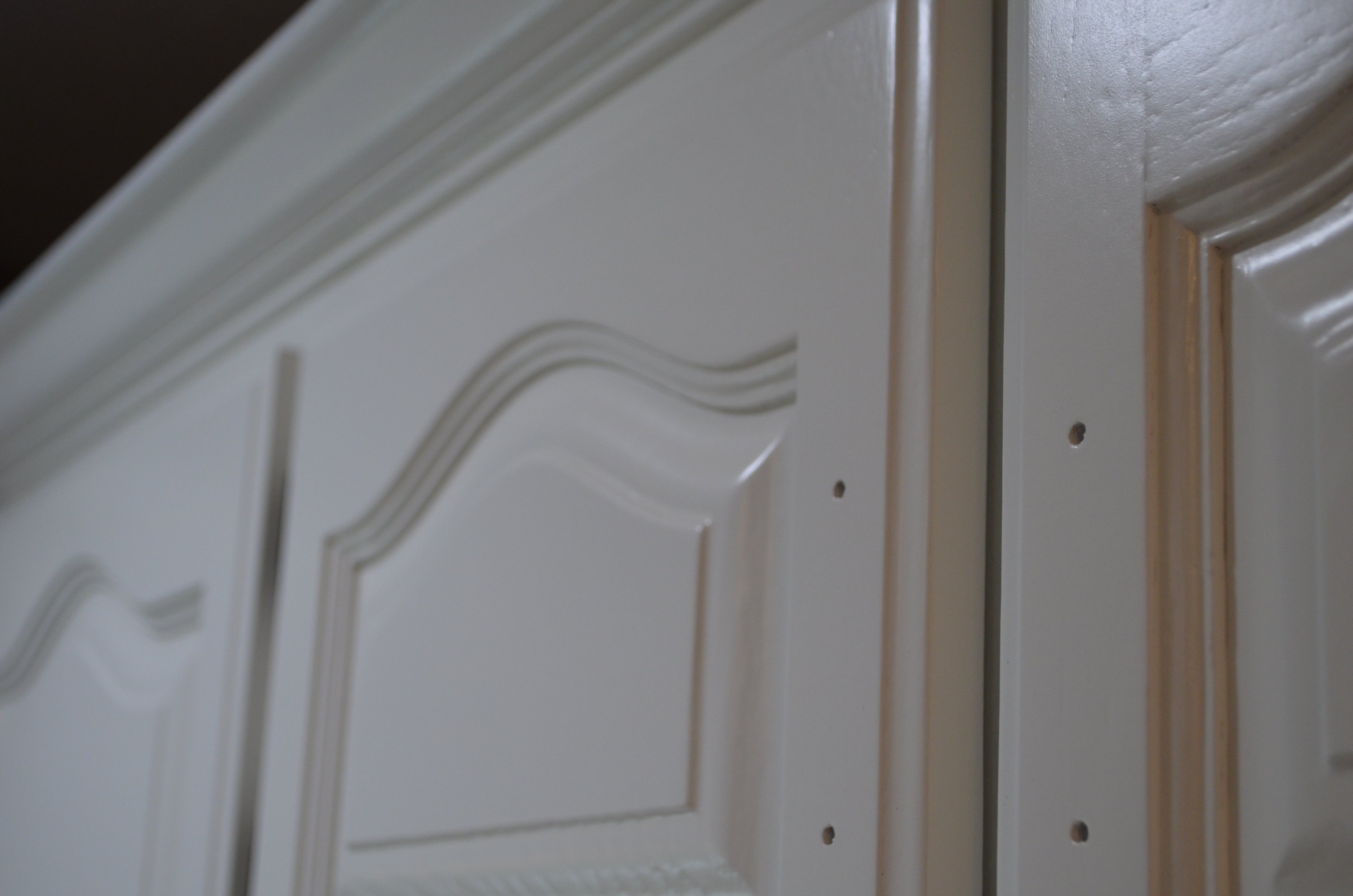 Close up image of small cabinets painted white with no handle.