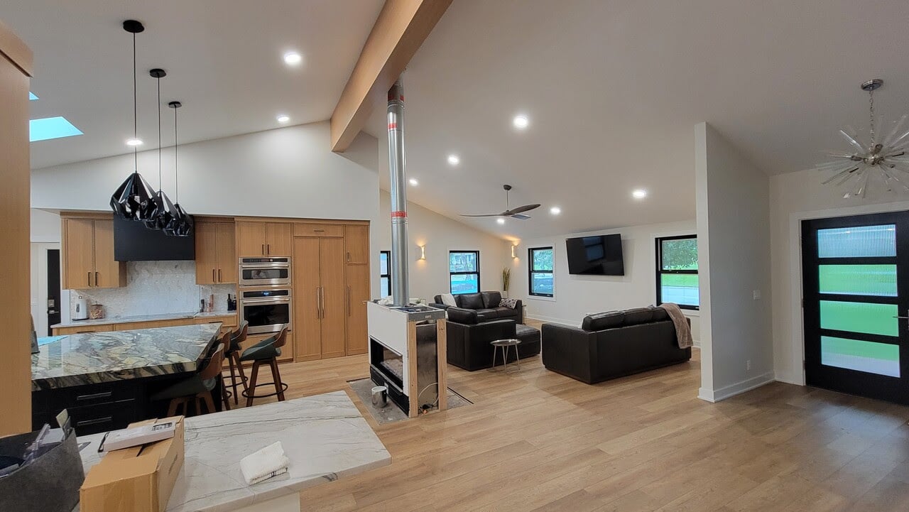 Kitchen and living room with white walls and light wood new floors.