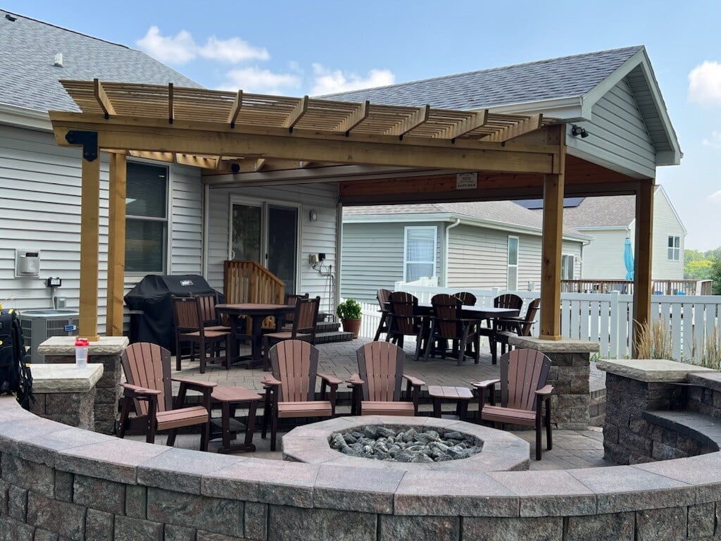 Wooden deck and pergola lightly stained a warm wood tone brown with outdoor patio furniture and fireplace.