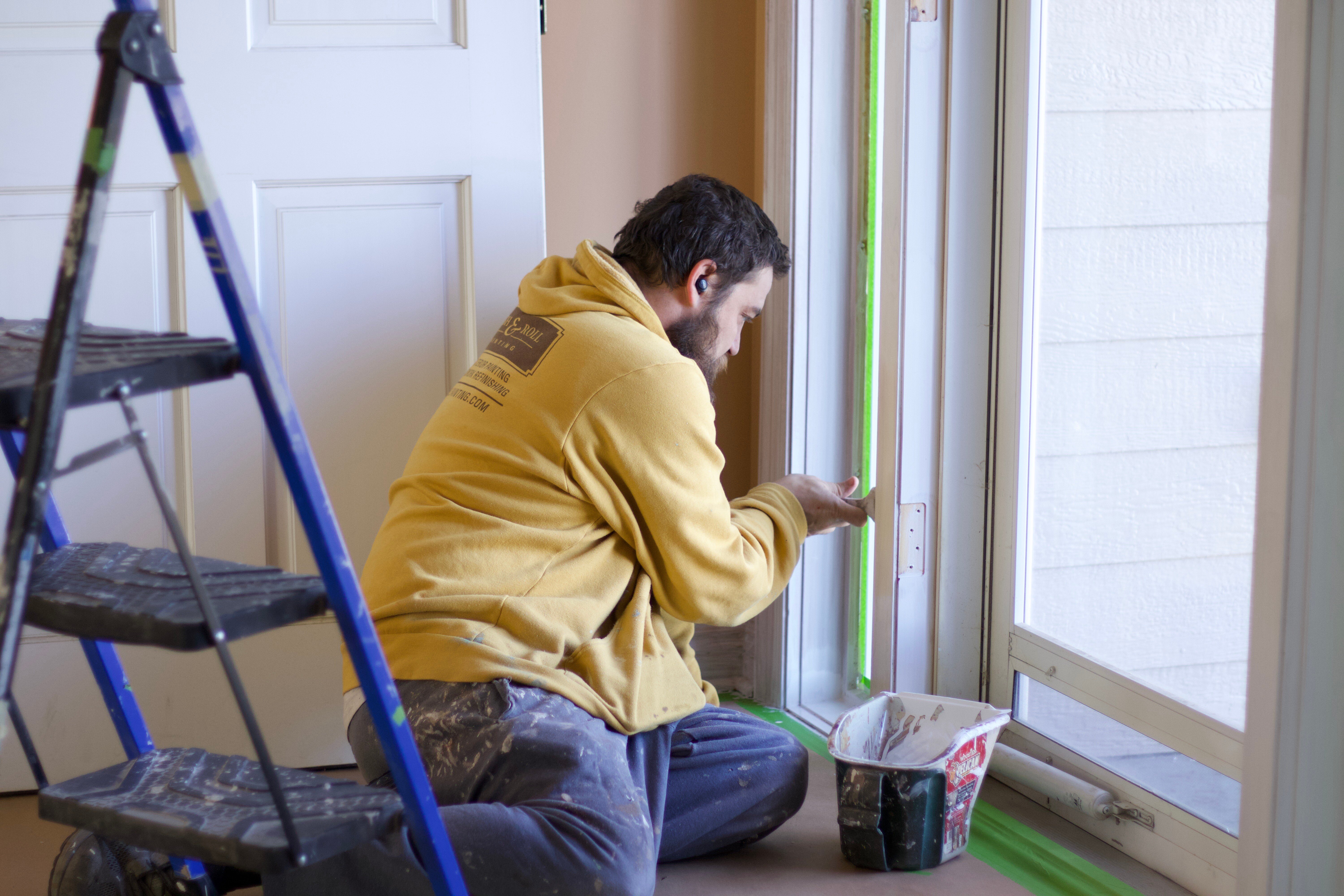 Painter painting interior door trim white with a brush in Omaha, NE.