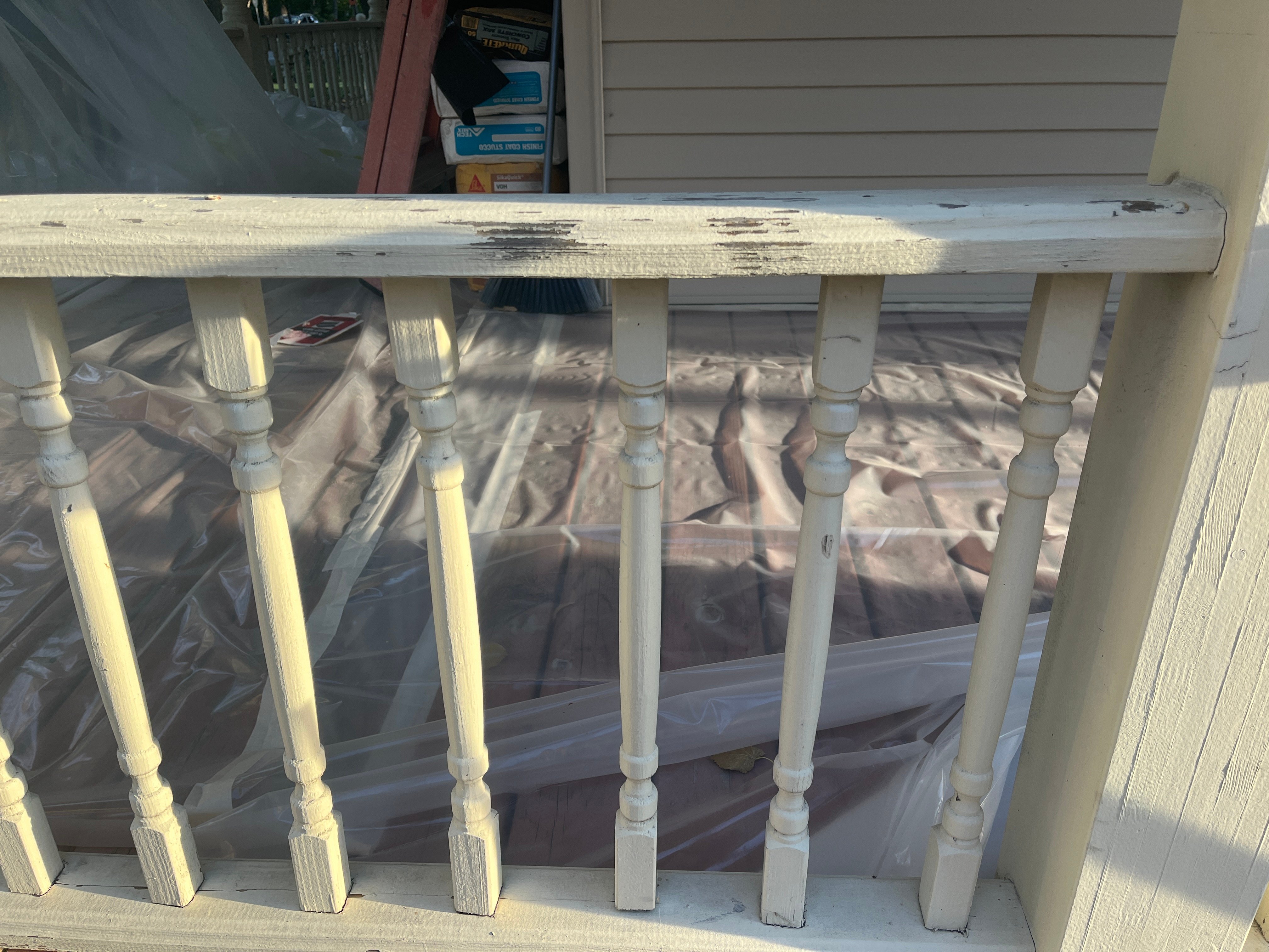 Front porch railing on exterior of your house with chipping white lead paint.