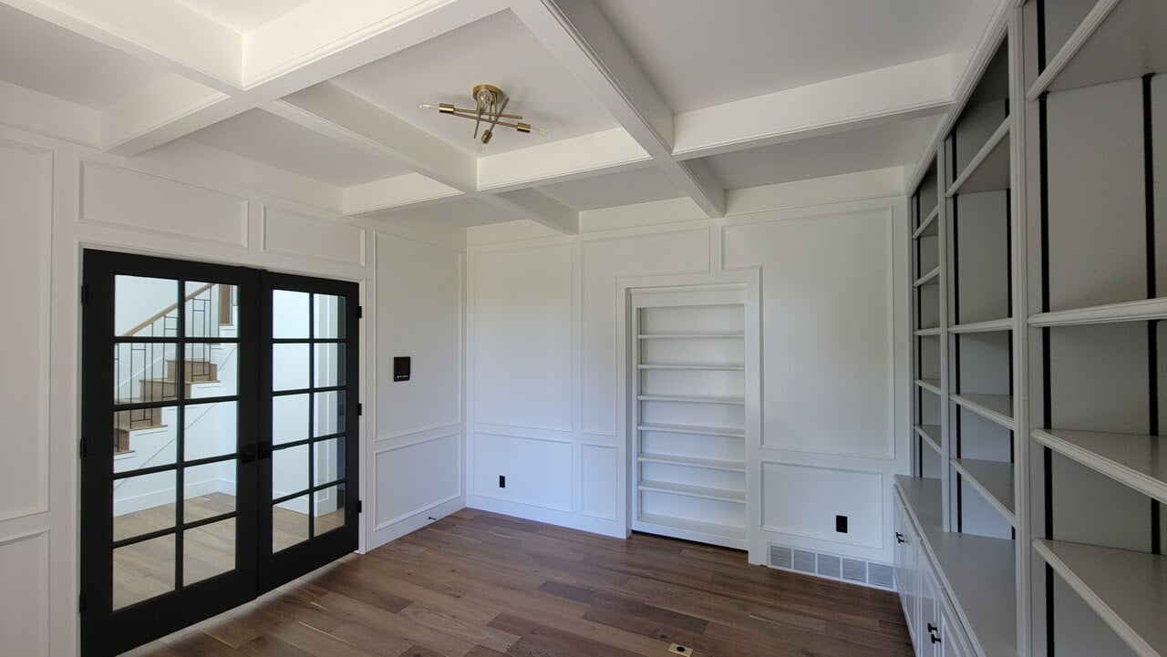 White walls and ceiling in home office space with wood floors and black window glass door.