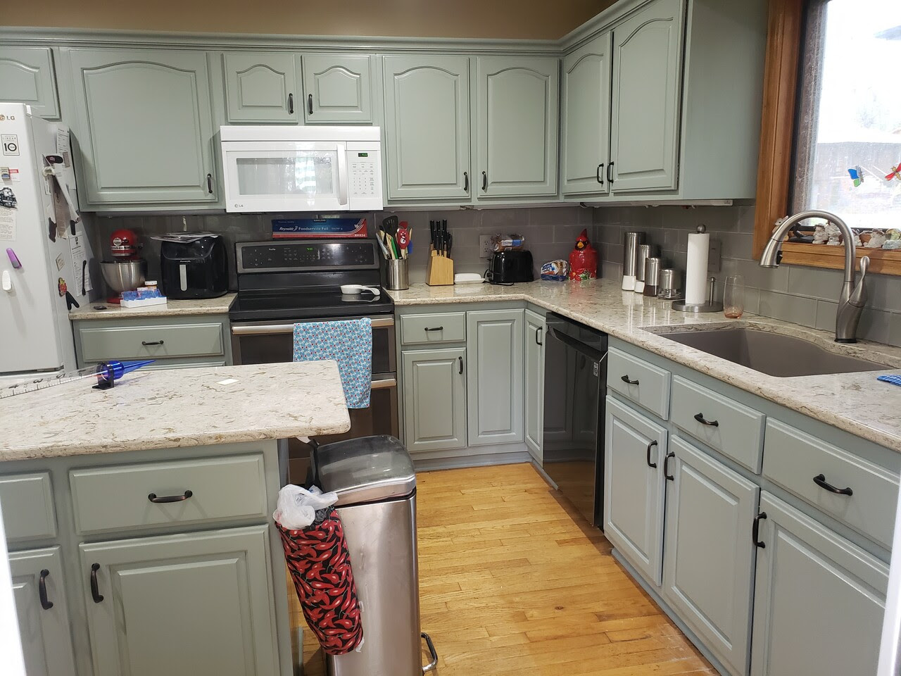 Light green cabinets in medium sized kitchen. 