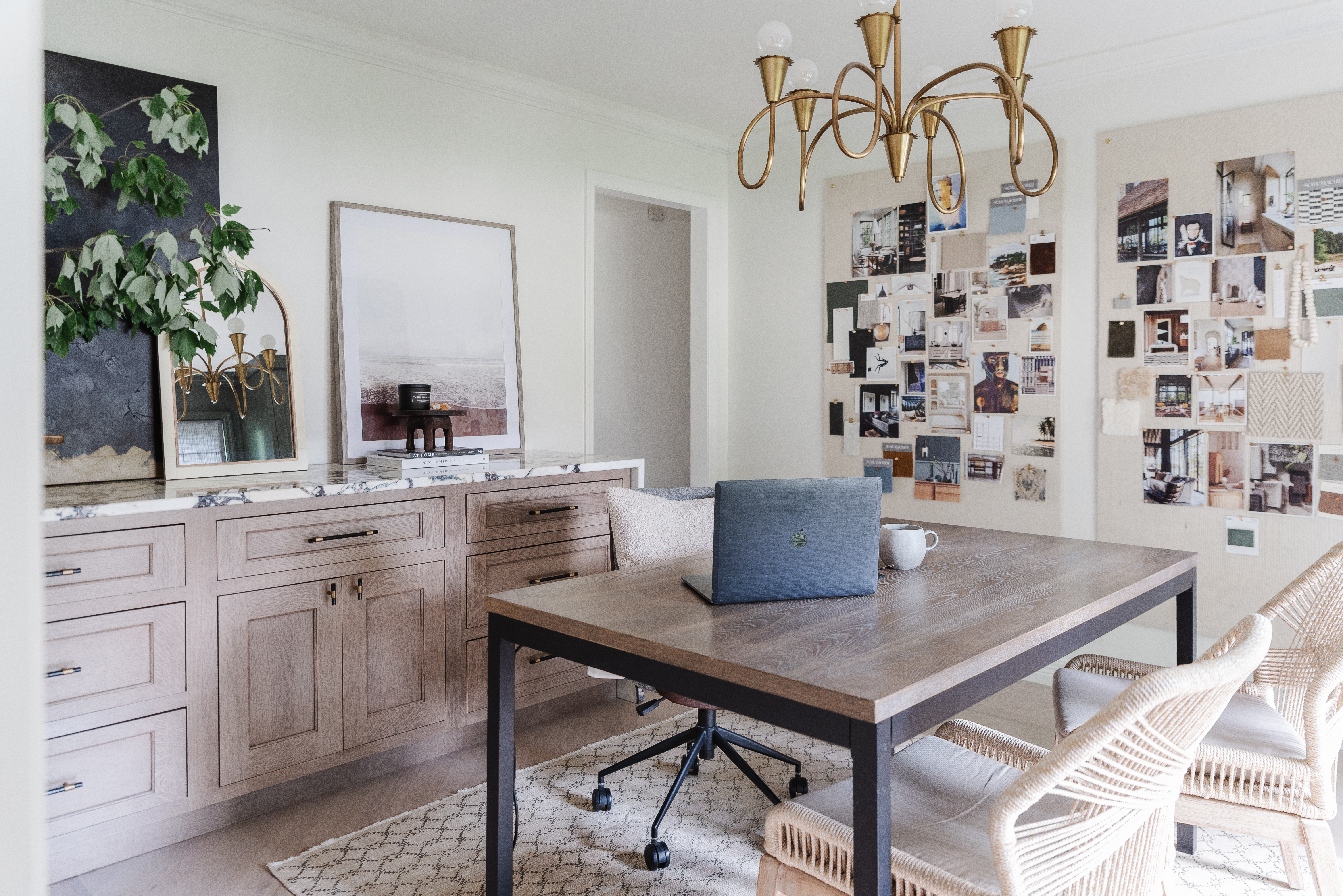 Home office with white walls and warm neutral wood tones and desk in the middle of the room.