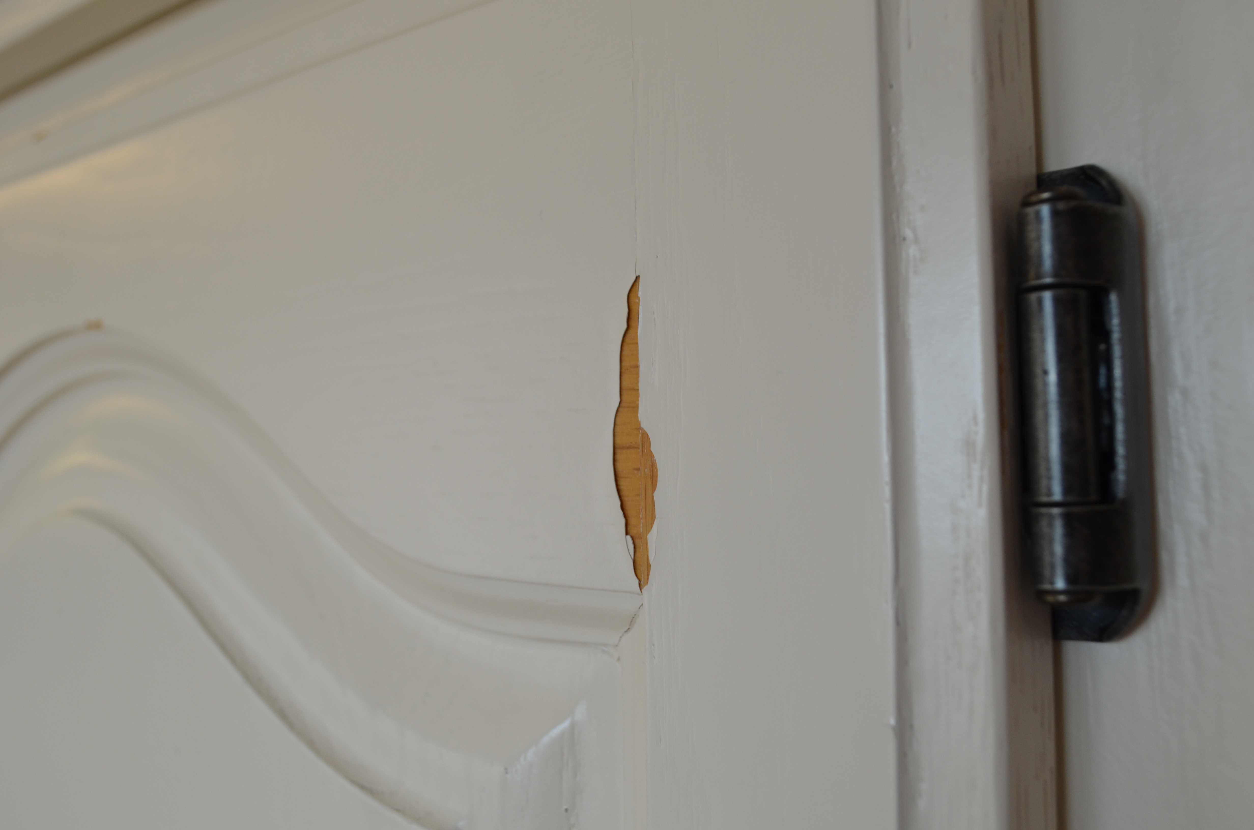 White painted cabinet with peeled spot, revealing oak wood.