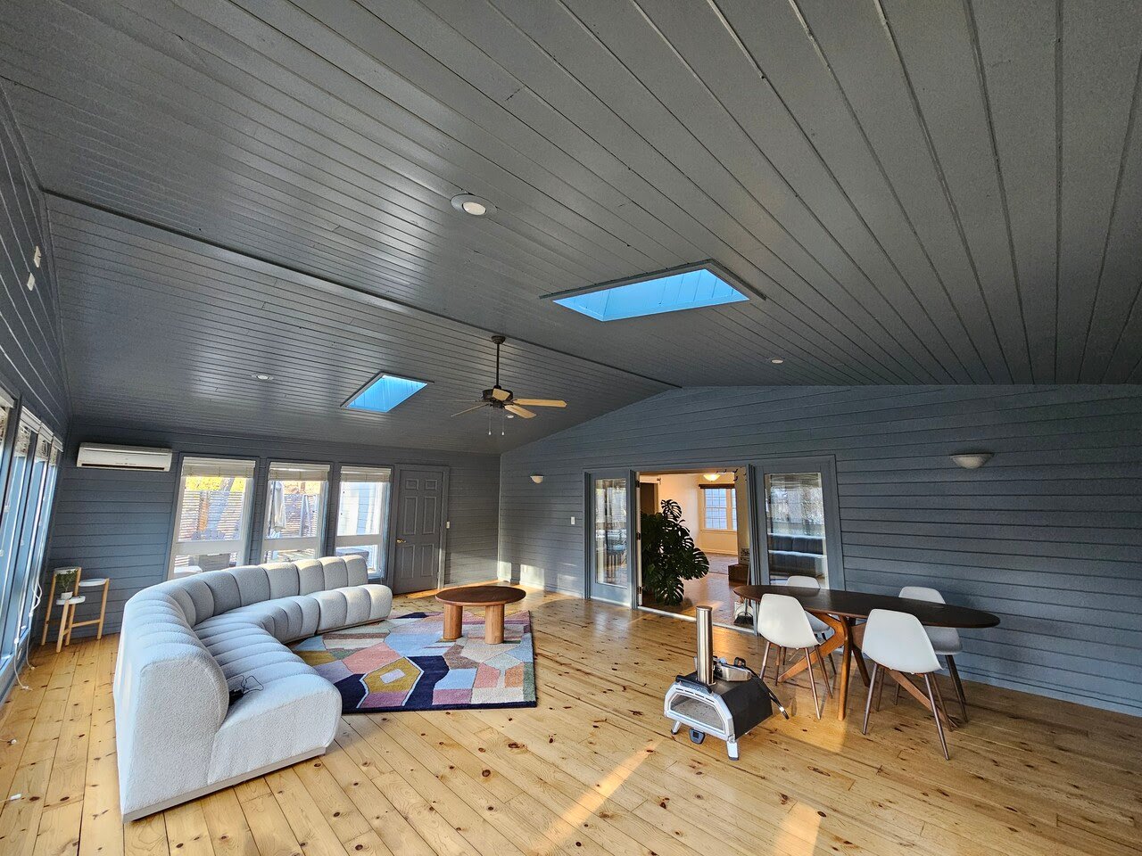 Sunroom painted a dark color with warm wooden floors and a large couch.