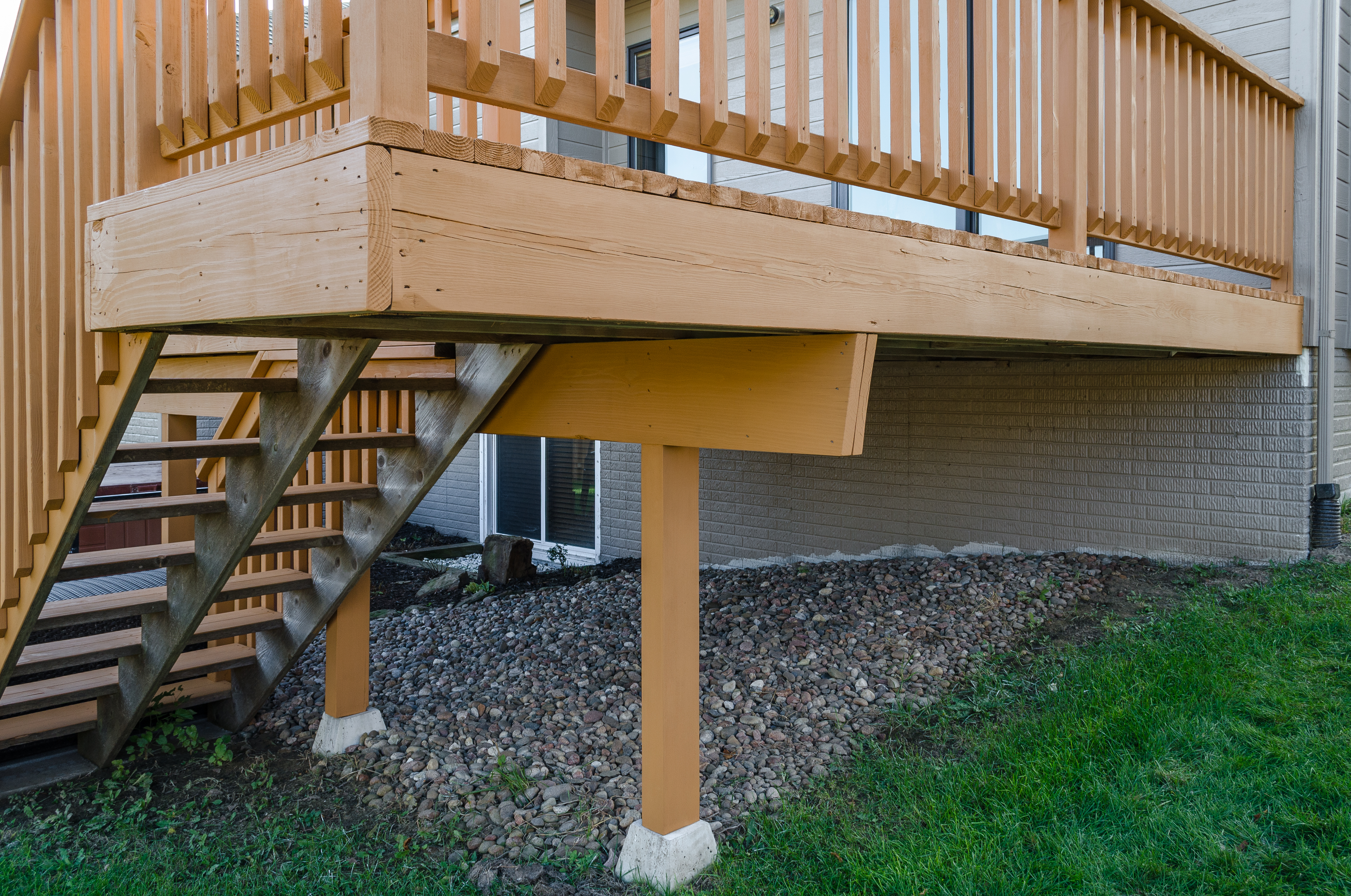 Outside corner of a small deck with a light stain on the wood.