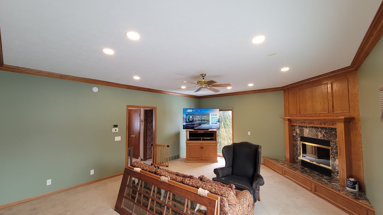 Living room with a white ceiling and walls painted a safe green with golden oak trim and furniture.