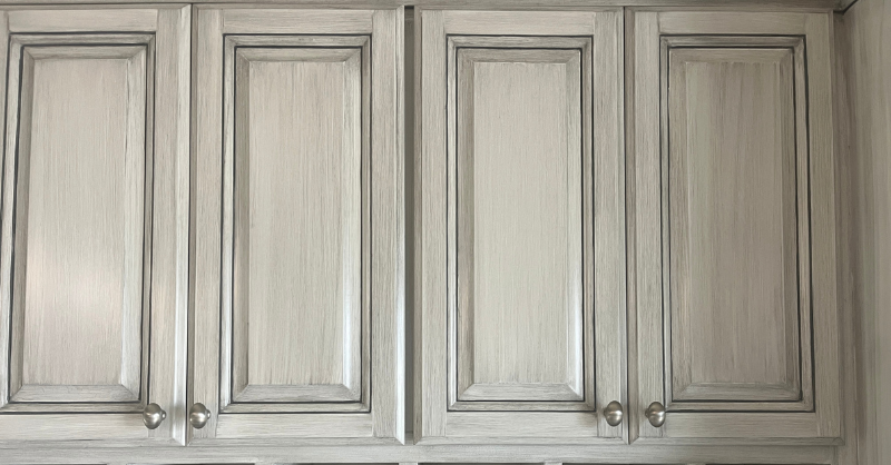 White cabinet doors with a light grey glaze and silver knobs.