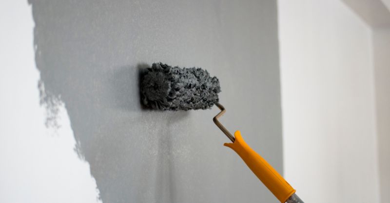 Gray paint being rolled on to wall.