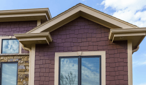 Deep red painted exterior peak of a home. With light brown trim. 